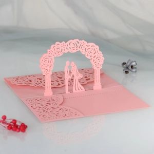 Close-up of laser-cut 3D rose arch and couple silhouette on pink wedding invitation