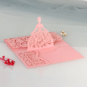 Macro detail of laser cut 3D pink dress silhouette on pearlescent invitation card