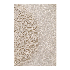 Macro detail of laser-cut rose pattern on champagne gold glitter wedding invitation card