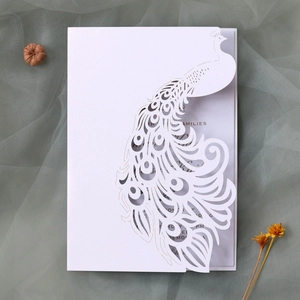 Detail of white laser-cut peacock wedding invitation with intricate hollow patterns