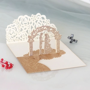 Macro detail of laser-cut 3D wedding invitation with gold glitter rose and couple figures