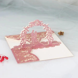 Macro detail of laser cut 3D pink glitter wedding card with silhouette of a kissing couple