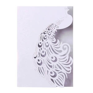 Close-up of laser-cut white wedding card with intricate peacock feather cutout design