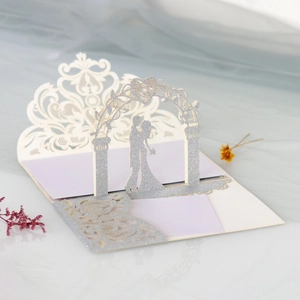 Detail of laser-cut wedding card with silver glitter couple silhouette under archway