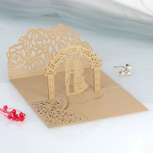 Dettaglio dell'invito di nozze 3D tagliato al laser in oro champagne con pizzo floreale