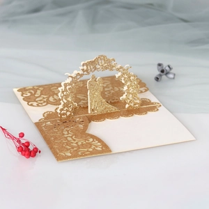 Close-up of laser-cut 3D wedding card with gold glitter finish and bride-groom silhouette