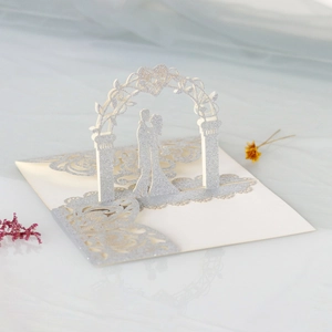 Macro detail of laser cut 3D wedding card featuring silver glitter arch and bride silhouette