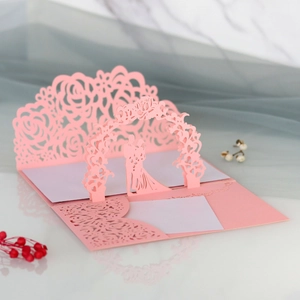 Dettaglio macro dell'invito di nozze 3D tagliato al laser con coppia e rose rosa