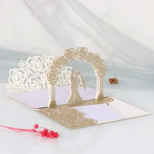 Macro shot of a 3D pop-up wedding card featuring laser-cut gold glitter roses and couple
