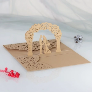 Detail of laser-cut wedding invitation featuring a champagne gold floral arch and couple