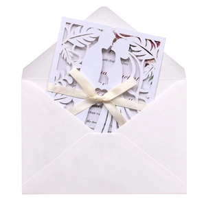 Macro detail of laser cut wedding invitation with white ribbon and couple silhouette