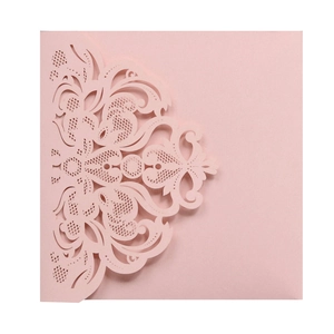 Close-up of laser-cut pink wedding invitation with ornate European floral patterns