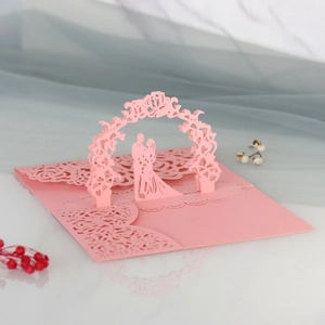 Dettaglio del biglietto nuziale 3D rosa con coppia tagliata al laser sotto un arco