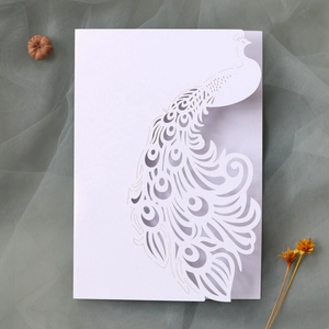 Macro shot of white laser-cut peacock wedding invitation with intricate hollow patterns