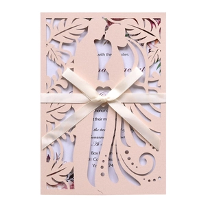 Close-up of laser-cut wedding invitation with romantic silhouette and satin ribbon bow