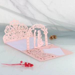 Macro detail of laser cut 3D pink wedding card showing bride and groom silhouette