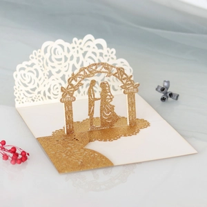 Detail of laser-cut gold glitter wedding card with 3D flower arch and couple silhouette