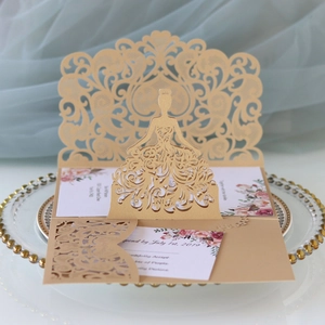 Detail of laser-cut gold wedding invitation with elegant girl silhouette and floral inner card