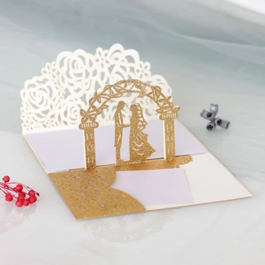 Detail of 3D laser-cut wedding card featuring golden glitter couple silhouette art