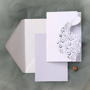 Macro detail of laser-cut peacock wedding invitation set with lilac inner card