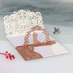 Detailed macro of laser-cut 3D wedding invitation with rose gold glitter silhouette