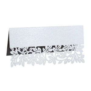 Macro detail of laser cut white leaf table card with pearlescent shimmer and floral pattern