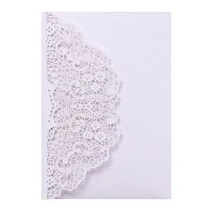Close-up of intricate laser-cut lace pattern on white wedding invitation card paper
