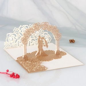 Macro view of laser-cut 3D pop-up wedding card with glittery champagne gold floral arch