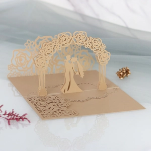 Detail of laser cut 3D pop-up wedding invitation featuring a golden floral arch silhouette
