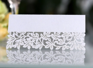 Macro shot of white laser-cut floral wedding place card with pearlescent finish