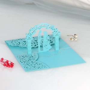Dettaglio dell'invito di nozze 3D tagliato al laser con arco floreale azzurro e coppia