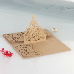 Macro detail of laser-cut 3D girl pop-up wedding invitation card in gold pearl paper