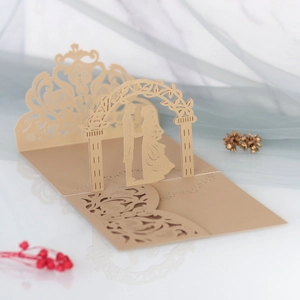 Macro shot of 3D laser-cut wedding card featuring bride and groom silhouette under archway