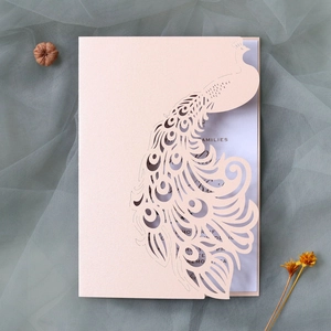 Macro shot of laser-cut peacock wedding invitation with elegant hollow patterns