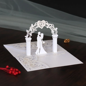 Detail of 3D laser-cut wedding invitation featuring a romantic couple under heart arch