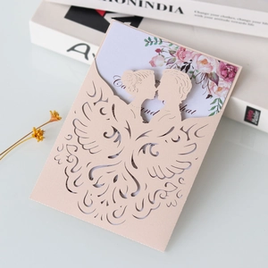Macro shot of laser-cut wedding invitation featuring pink silhouettes and floral inner card