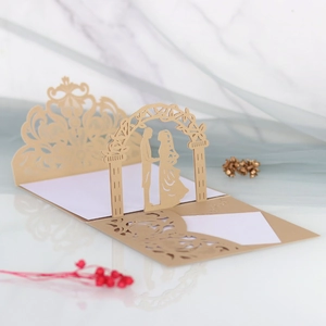 Detail of laser-cut gold wedding invitation featuring bride and groom under a floral arch