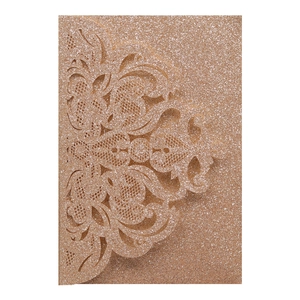 Close-up of laser cut rose gold glitter wedding invitation with floral patterns
