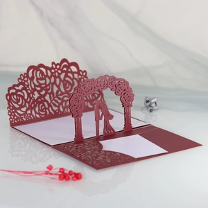 Macro detail of laser-cut burgundy wedding card with 3D bride and groom silhouette