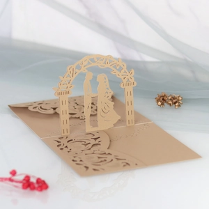 Detail of laser-cut 3D wedding invitation with champagne gold silhouette under flower arch