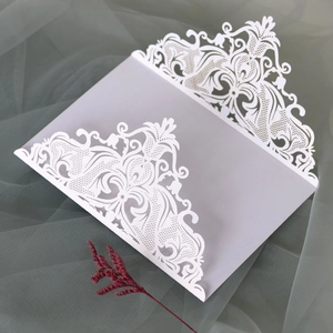 Macro detail of intricate laser-cut floral patterns on white lace wedding invitation