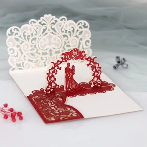 Close-up of laser-cut 3D wedding invitation with red glitter and romantic silhouette