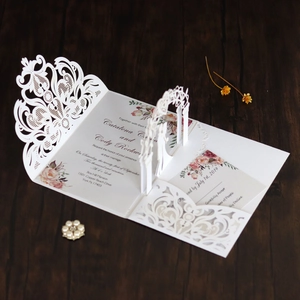 Macro detail of laser-cut wedding invitation with intricate lace gate and pop-up floral design