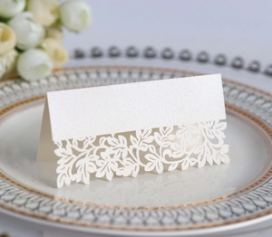 Elegant laser-cut leaf place card in pearlescent white on a wedding table setting