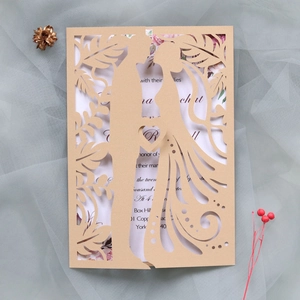 Detail showing laser-cut couple silhouette and floral patterns on cream wedding invitation