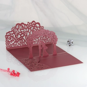 Detail of 3D laser cut wedding invitation with burgundy roses and couple silhouette
