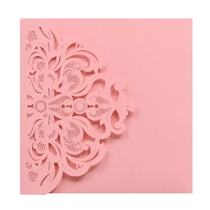 Detail of pink laser-cut wedding invitation with intricate floral vine hollow patterns
