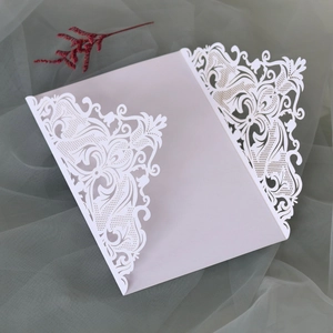 Macro detail of laser-cut lace floral pattern on pink pearlescent wedding invitation