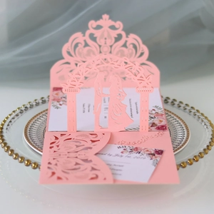 Detail of pink laser-cut wedding invitation with intricate archway and silhouette design