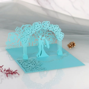 Close-up of 3D pop-up wedding invitation featuring laser-cut floral arch and kissing couple